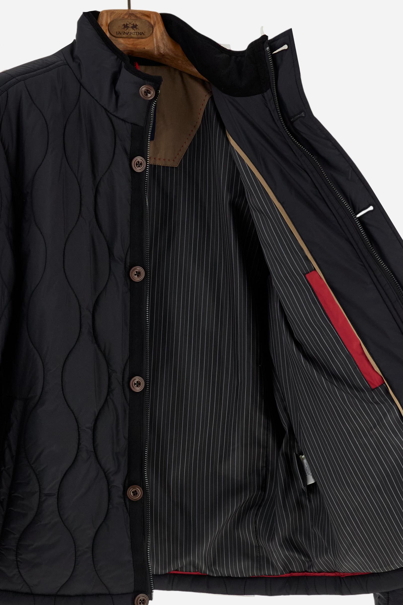 Men’s quilted nylon husky jacket with high collar. Front closure with customized zip and large faux-leather buttons. Interior lined with striped bicolor polyester. Contrast details on the inside (pockets, profiles, back-neck tab). Clean design with chest pocket closed by zip and vertical side pockets. Adjustable back straps with metal snap buttons. Logo patches on the sleeves and multicolor embroidered lettering on the outer collar. Part of the Guards capsule. Regular fit. Model wears size L. - Black