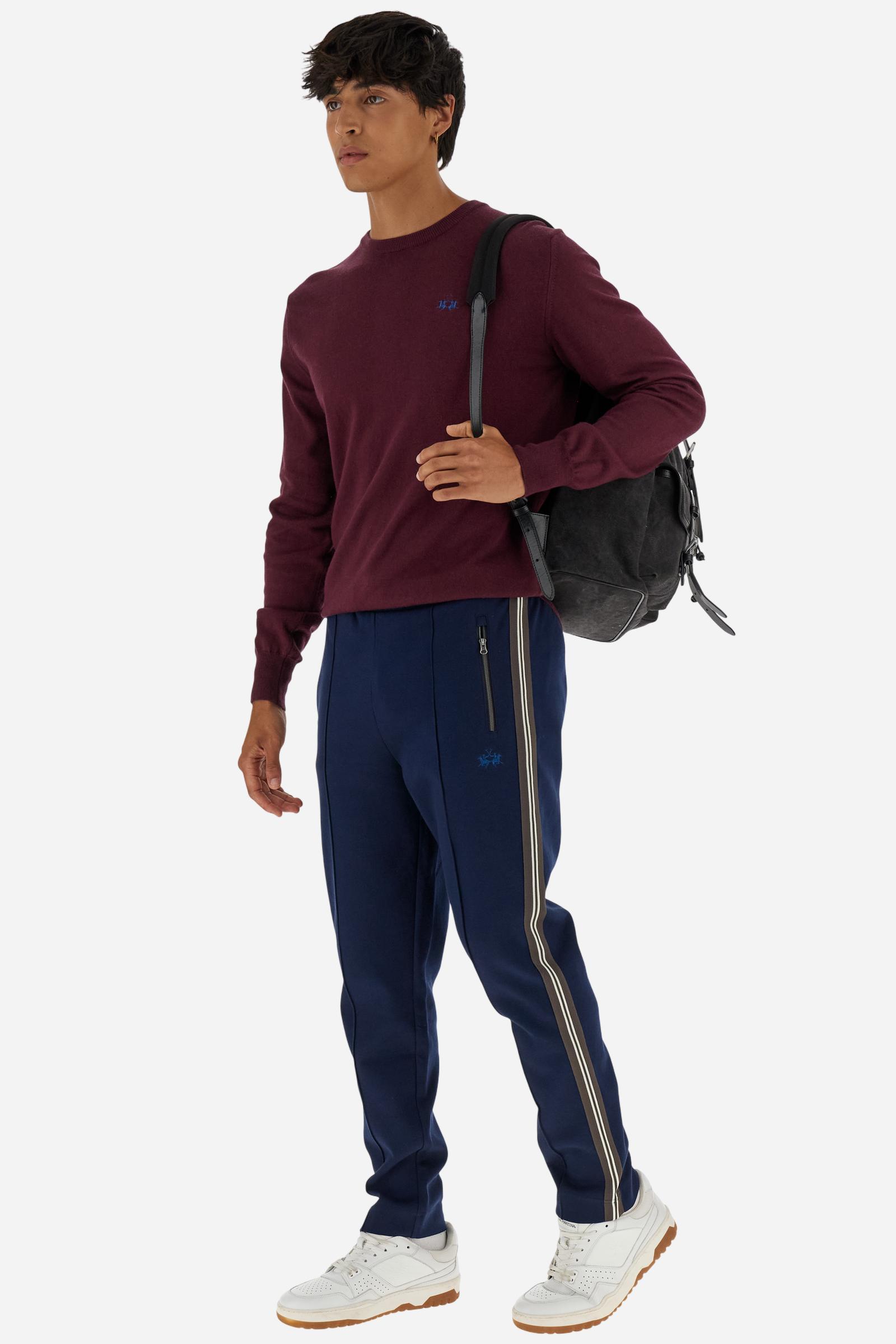 Men’s joggers made of 100% cotton interlock fleece with a bicolor design. Elastic waistband with drawstring for a customizable fit. Two zipped side pockets add practicality, while multicolor striped tape decorates both sides. A vertical crease on the front leg adds refinement to this sporty style. Small embroidered logo in contrast under the left pocket. Regular straight-leg fit for a classic, comfortable silhouette. Model wears size L. - Navy