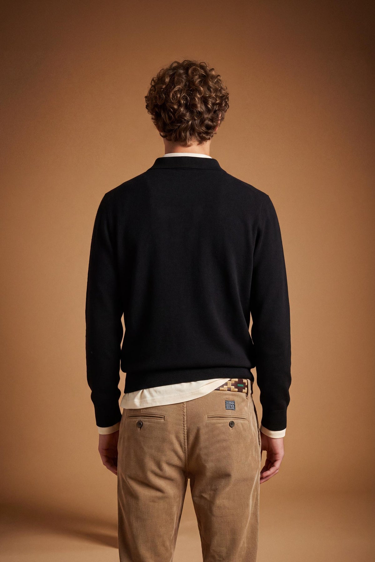 Men's long-sleeve polo made from 100% merino wool offers a comfortable fit, classic knitted collar, ribbed cuffs, and a subtle embroidered logo on the chest. - Black
