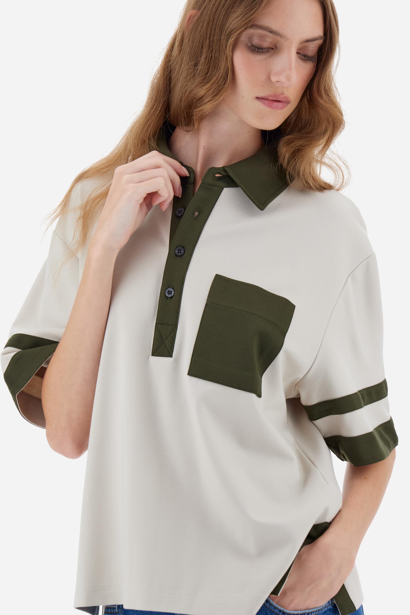 Women’s short-sleeve polo shirt in high-quality solid-colour viscose blend interlock. Classic collar with deep three-button placket, contrast fabric details on body and sleeves. Large embroidered logo on the back. Boxy, straight fit at the hips for a modern and comfortable silhouette. The model wears size L. - Creme Brulè/Kombu Gr