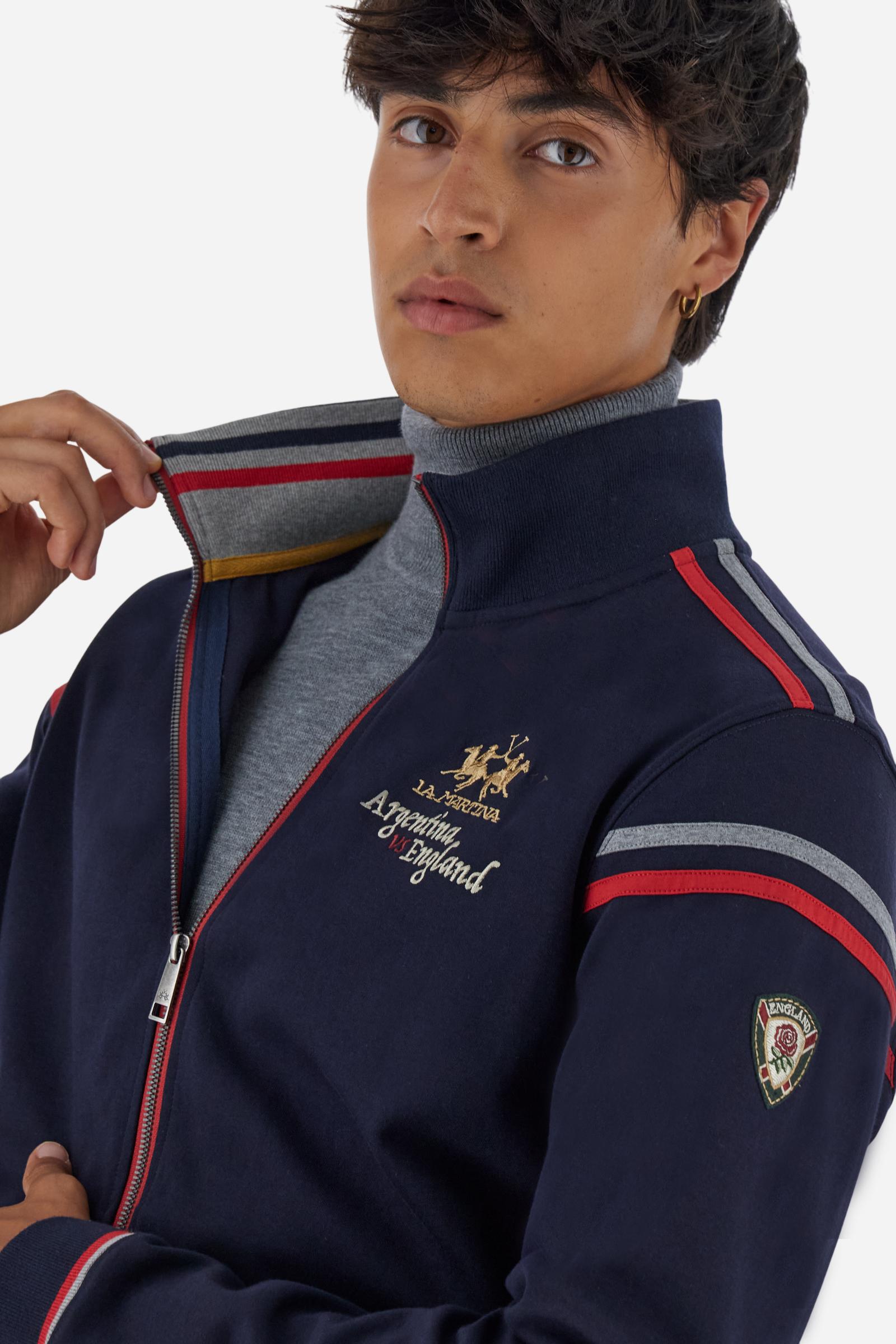 Men's long-sleeved, full-zip solid colour sweatshirt. Made of soft cotton-blend fleece. Features a convenient front opening with eye-catching contrasting colour details. The two-tone coloured band patterns are inspiredby the theme of the Argentina VS England teams. The small logo on chest adds a subtle touch of brand identity. The regular fit ensures a comfortable and relaxed silhouette. The model is wearing a size L. - Navy