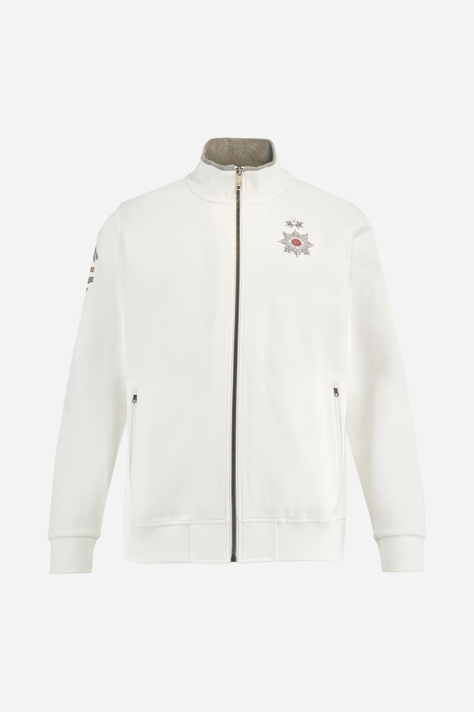 Men's long-sleeved, full-zip solid colour sweatshirt. Made of stretch cotton-blend piqué. Design with front opening fastened by a zip, high collar in two-tone ribbing. Solid colour ribbed cuffs and waistband. The small brand logo and Guards crest are embroidered in multi-coloured thread on the chest. On the right sleeve, there is another embroidery of a crest inspired by the British royal household. The regular fit silhouette is practical for everyday wear. The model is wearing a size L. - Off White