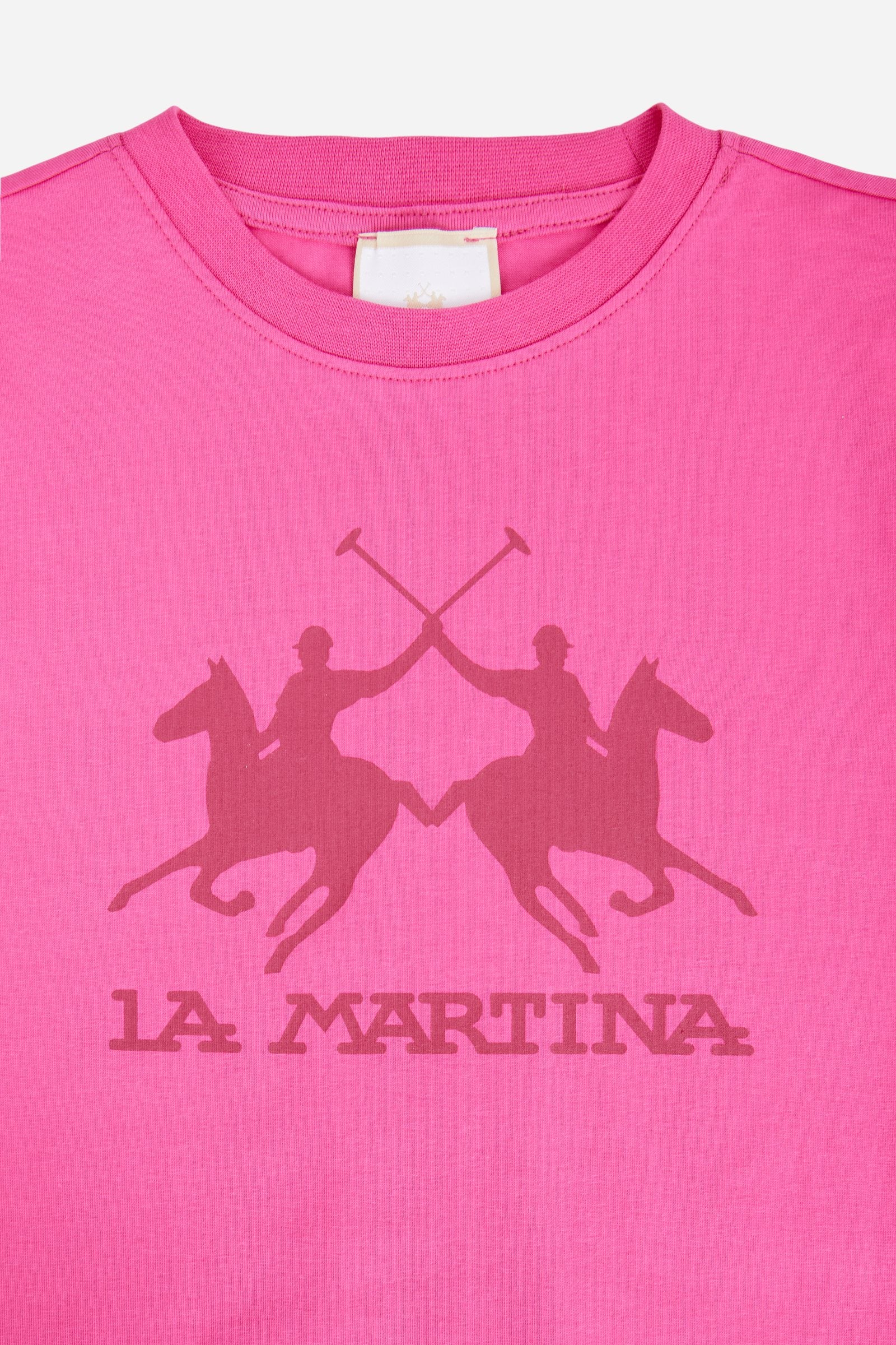 Short-sleeved T-shirt for girls made from soft 100% cotton jersey in a solid colour. The style features a regular fit and tonal ribbed crew neck. The maxi front print, featuring the iconic crossed polo players logo and La Martina lettering, enhances the garment with a sporty and recognisable style. - Fandango Pink