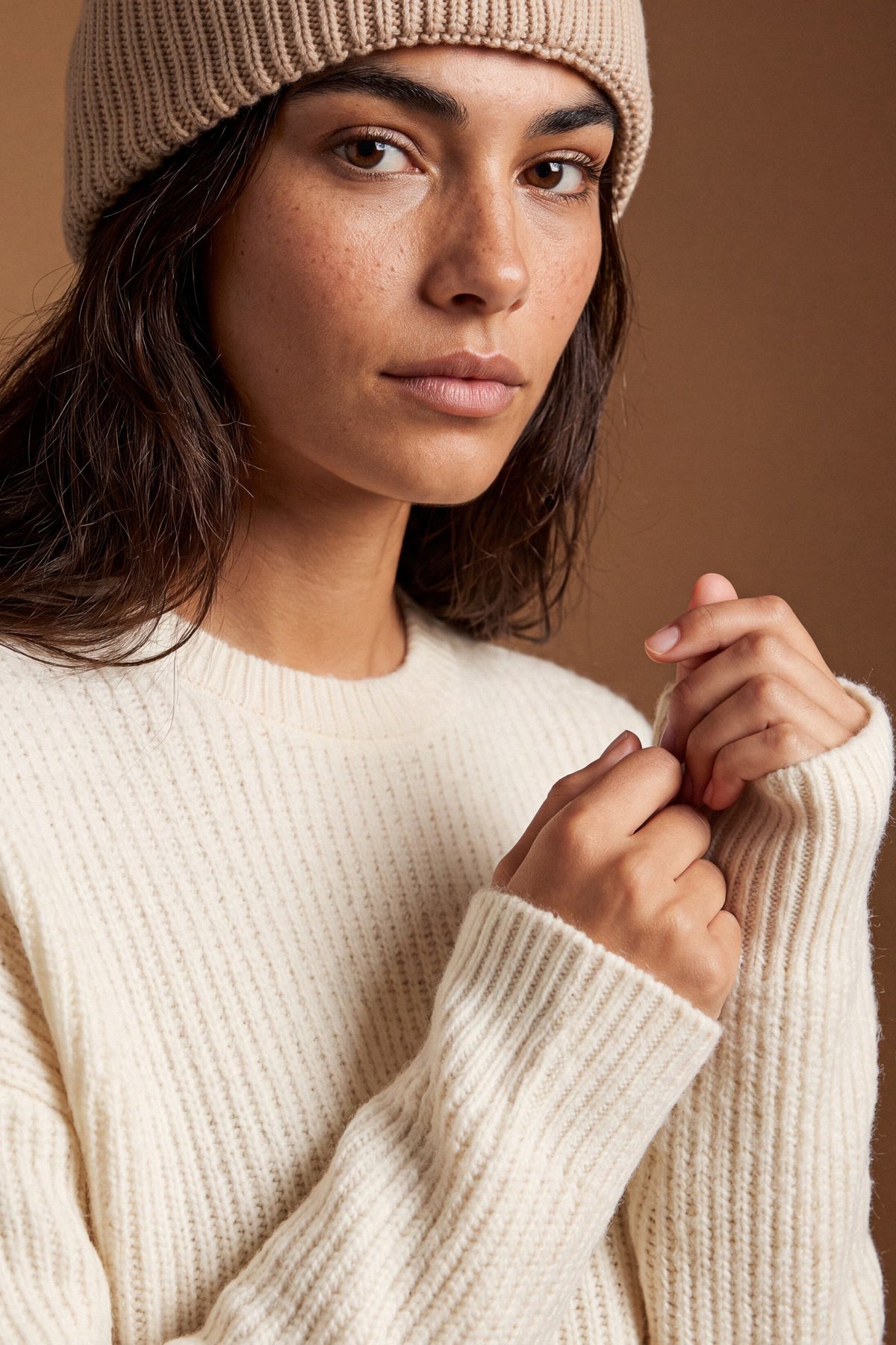 Soft lambswool women's sweater with vertical ribbed knit, relaxed fit, dropped shoulders, cropped length, and a subtle embroidered logo on the back neckline. - Antique White