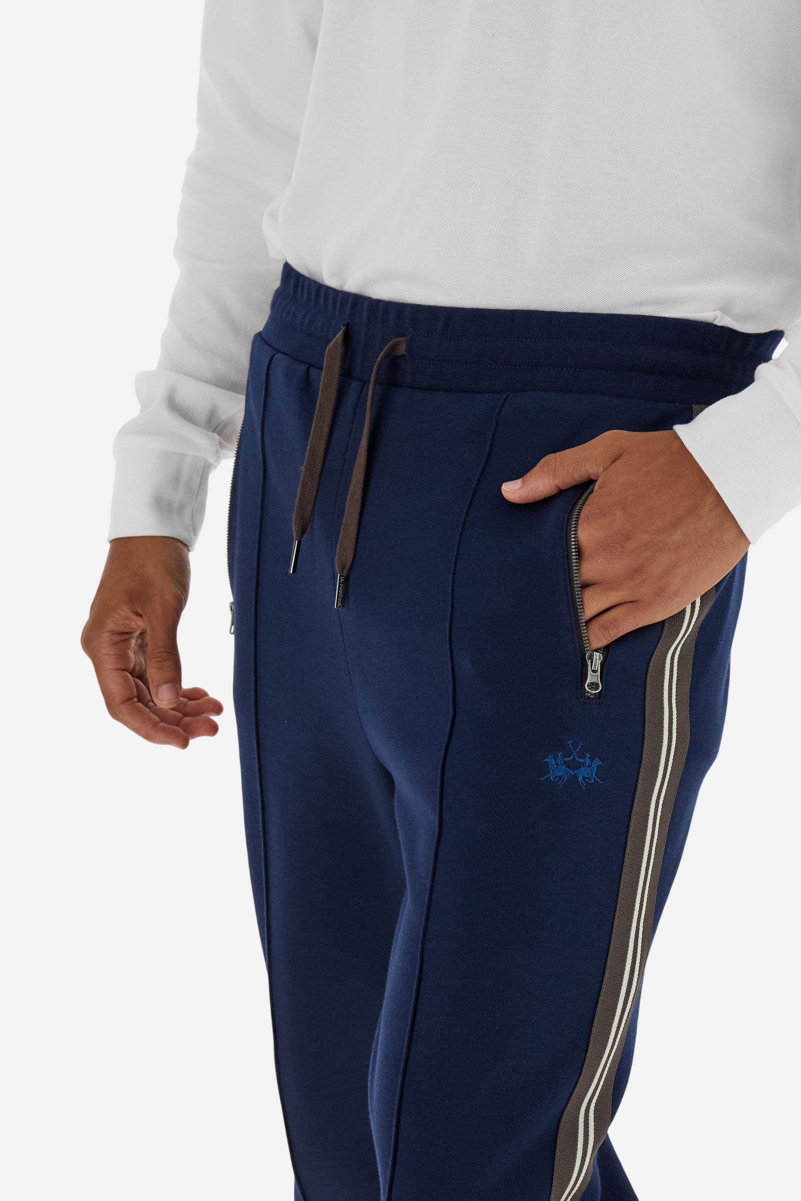 Men’s joggers made of 100% cotton interlock fleece with a bicolor design. Elastic waistband with drawstring for a customizable fit. Two zipped side pockets add practicality, while multicolor striped tape decorates both sides. A vertical crease on the front leg adds refinement to this sporty style. Small embroidered logo in contrast under the left pocket. Regular straight-leg fit for a classic, comfortable silhouette. Model wears size L. - Navy