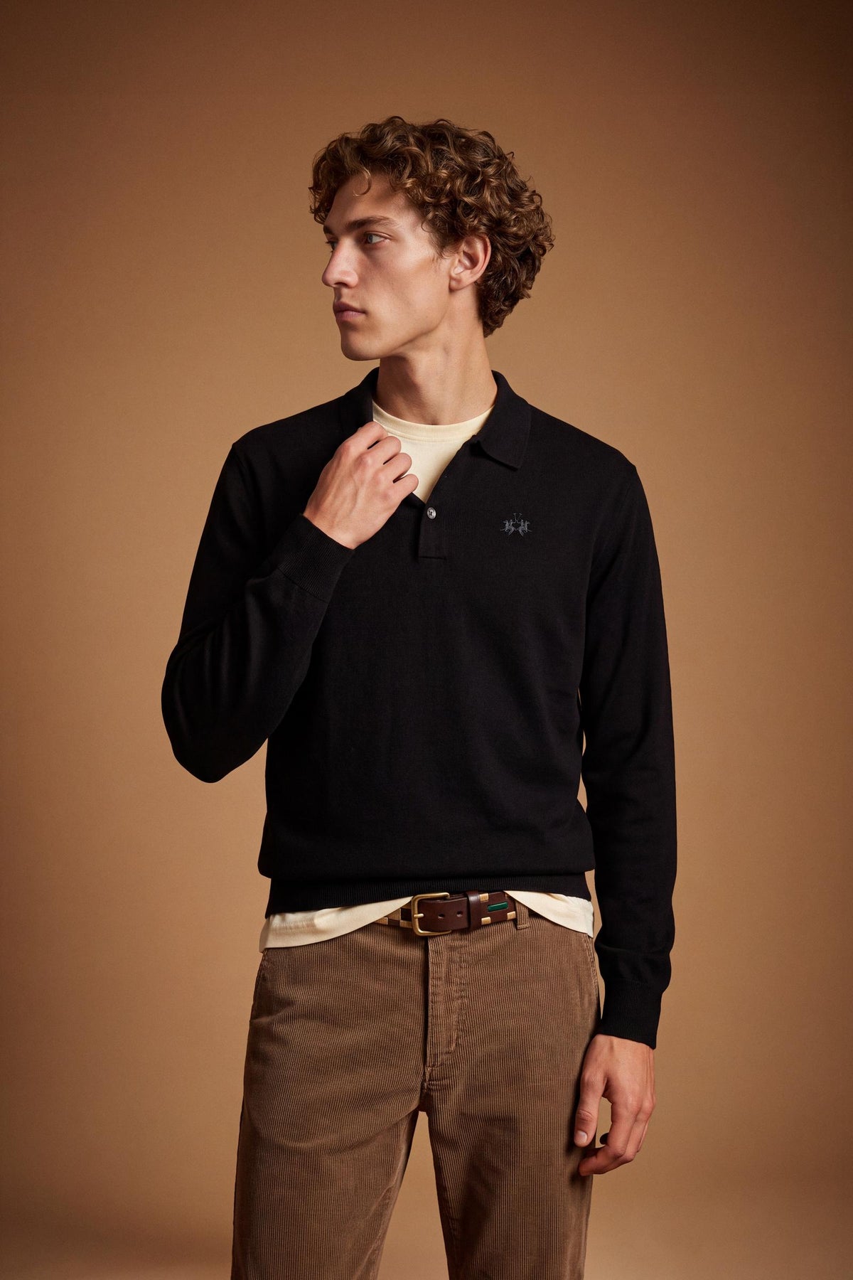 Men's long-sleeve polo made from 100% merino wool offers a comfortable fit, classic knitted collar, ribbed cuffs, and a subtle embroidered logo on the chest. - Black
