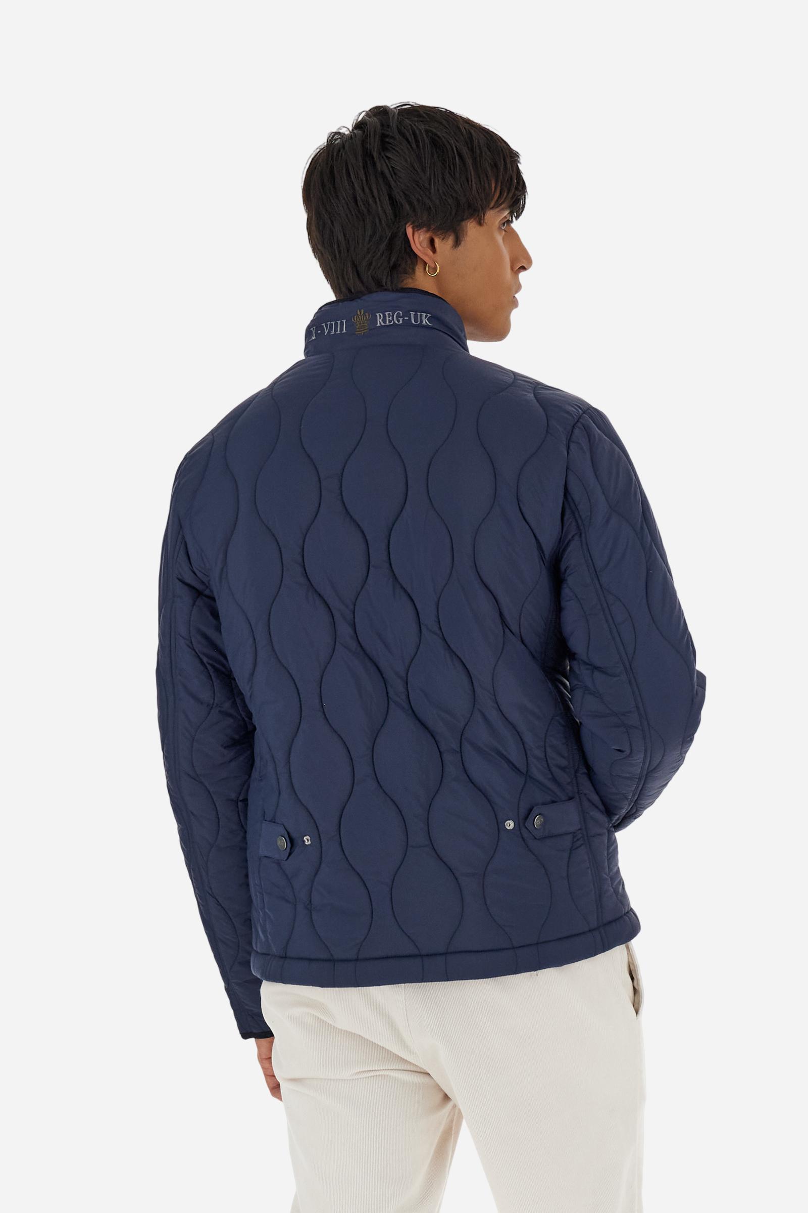 Men’s quilted nylon husky jacket with high collar. Front closure with customized zip and large faux-leather buttons. Interior lined with striped bicolor polyester. Contrast details on the inside (pockets, profiles, back-neck tab). Clean design with chest pocket closed by zip and vertical side pockets. Adjustable back straps with metal snap buttons. Logo patches on the sleeves and multicolor embroidered lettering on the outer collar. Part of the Guards capsule. Regular fit. Model wears size L. - Navy